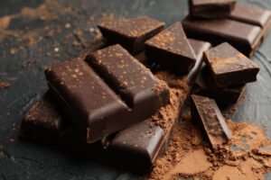 Cocoa powder and dark chocolate pieces on a dark surface